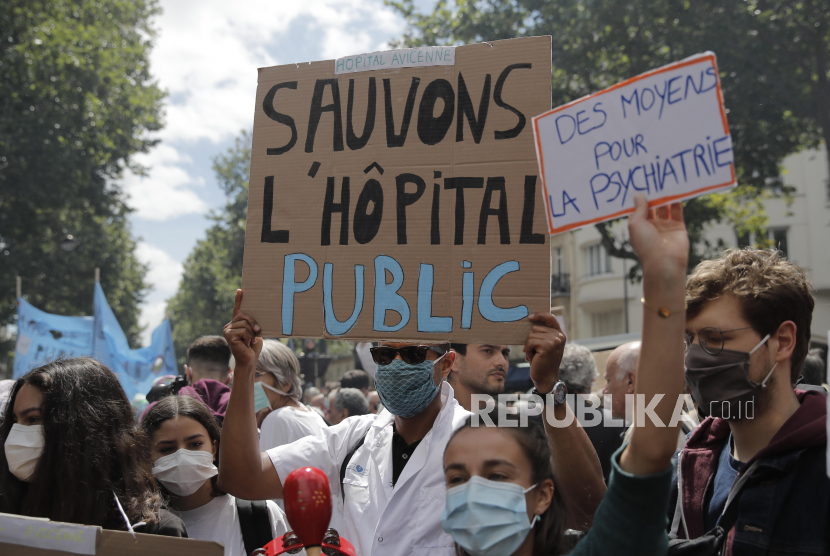 Pekerja rumah sakit memegang plakat, salah satunya bertuliskan 
