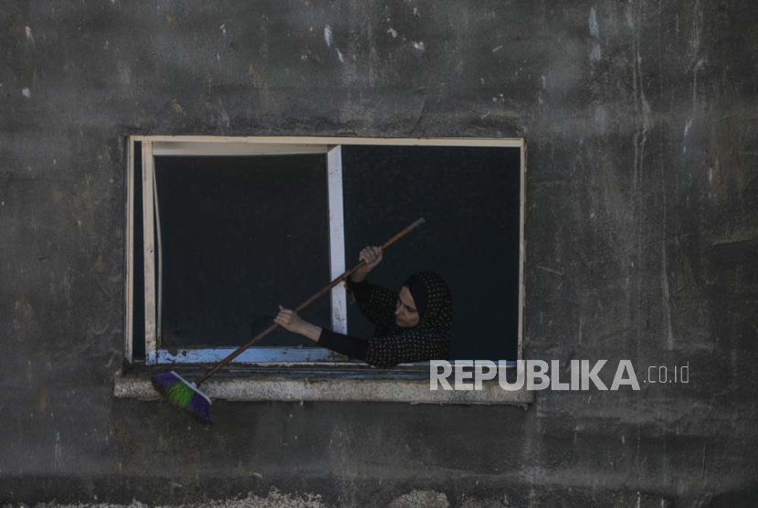 Seorang wanita Palestina membersihkan ambang jendela setelah serangan udara Israel, di kota Deir Al Balah, Jalur Gaza selatan, (4/4/2024).