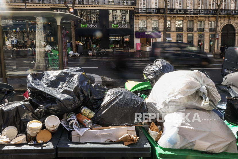  Orang-orang lewat di samping tong sampah yang penuh dengan sampah di Paris, Prancis. Tikus diburu dan kulitnya diolah menjadi sarung tangan
