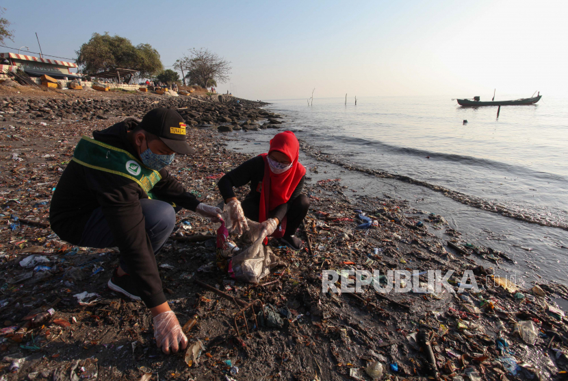 Warga memungut sampah di pinggir pantai kawasan Kedung Cowek, Surabaya, Jawa Timur, Ahad (29/8/2021). Kegiatan bersih-bersih sampah yang dilakukan oleh Tunas Hijau dan warga tersebut sebagai wujud kepedulian terhadap kebersihan lingkungan di kawasan pantai. 