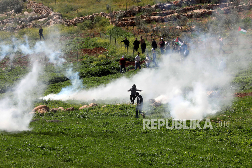 Warga Palestina mencari perlindungan dari gas air mata saat bentrokan dengan tentara Israel setelah protes di desa Bet Dajan dekat kota Nablus di Tepi Barat,  Jumat (17/3/2023).