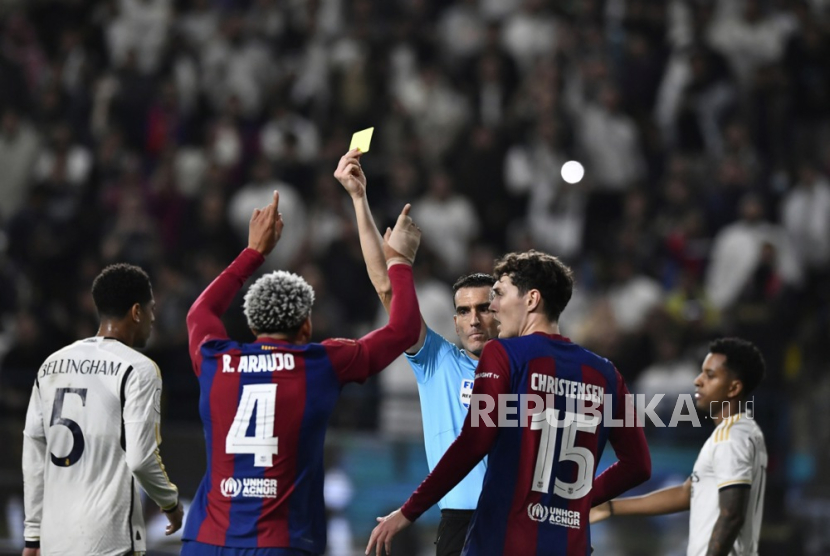 Wasit Juan Martinez memberikan kartu kuning kepada pemain Barcelona Ronald Araujo (kedua kiri) saat pertandingan final Piala Super Spanyol antara Real Madrid dan Barcelona di Al Awal Park di Riyadh, Arab Saudi, Senin (15/1/2024) dini hari WIB