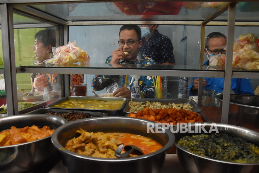 Gubernur DKI Jakarta Anies Rasyid Baswedan menikmati makan siang di Warteg Family yang menjadi sentra penyaluran bantuan pangan di kawasan Palmeriam, Kecamatan Matraman, Jakarta Timur, Kamis (14/10/2021). 