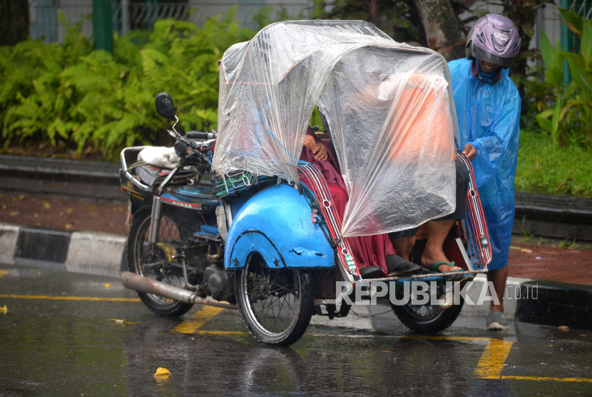 Tukang becak menaikkan penumpang saat hujan di kawasan Ngabean, Yogyakarta, Rabu (28/12/2022). Cuaca Hari Ini: Hujan Berpeluang Turun di Sejumlah Kota Besar di Indonesia