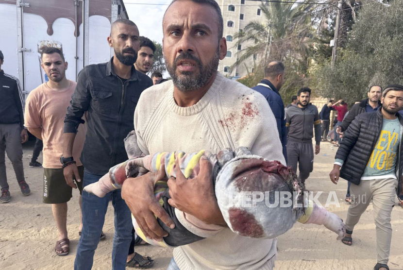 Seorang warga Palestina mengevakuasi seorang anak yang terluka pasca serangan Israel di Al Zawayda, Jalur Gaza tengah, Kamis, 28 Desember 2023.