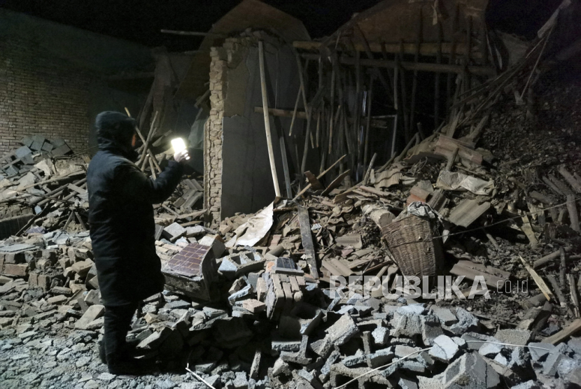 Seorang pegawai pemerintah melihat puing-puing sebuah rumah yang roboh akibat gempa bumi di daerah Jishishan di provinsi Gansu, Tiongkok barat laut, Selasa, (19/12/2023). 