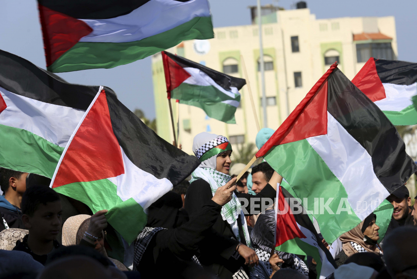 Para wanita mengibarkan bendera nasional mereka selama rapat umum menandai peringatan 46 tahun Hari Tanah, di dekat pagar perbatasan Jalur Gaza dengan Israel, timur Kota Gaza, Sabtu, 26 Maret 2022. UE Perbarui Dukungan untuk Palestina, Setujui Paket Bantuan Rp 2,4 Triliun