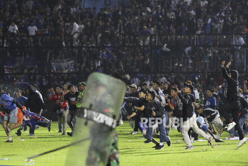 Soccer fans enter the pitch during a clash between supporters at Kanjuruhan Stadium in Malang, East Java, Indonesia, Saturday, Oct. 1, 2022. Panic following police actions left over 100 dead, mostly trampled to death, police said Sunday. (AP Photo/Yudha Prabowo)