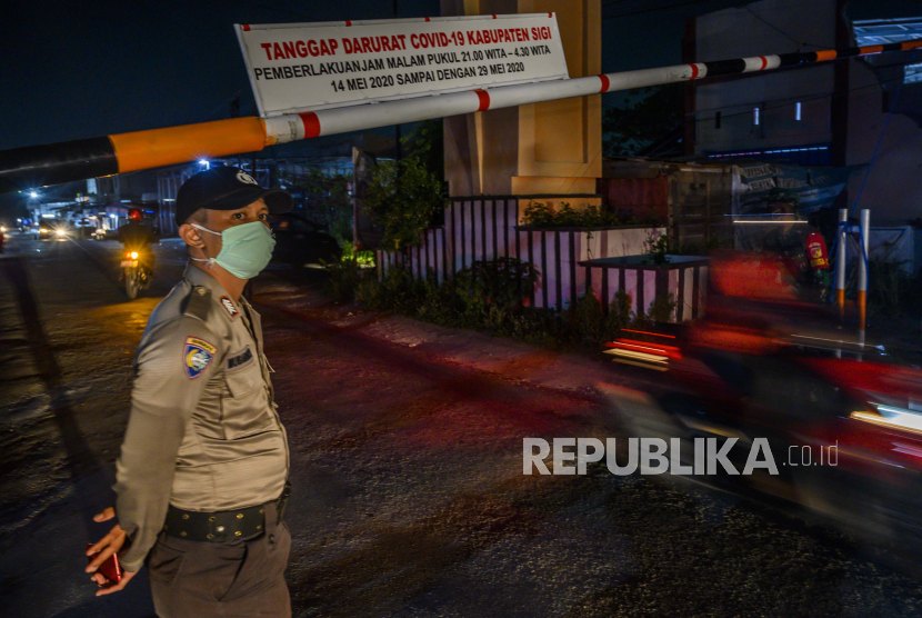 Petugas kepolisian berjaga di portal pintu masuk ke Kabupaten Sigi di Desa Baliase, Sigi, Sulawesi Tengah, Kamis (14/5/2020) malam. Pemerintah Kabupaten Sigi memberlakukan jam malam mulai 14 - 29 Mei 2020 antara pukul 21