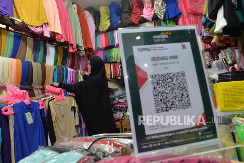 Pedagang kerudung merapihkan dagangannya di toko yang melayani pembayaran kode respons cepat berstandar nasional atau Quick Response Code Indonesia Standard (QRIS), di toko Ummi Krudung, Pasar Mayestik Jakarta, Jumat (6/3).