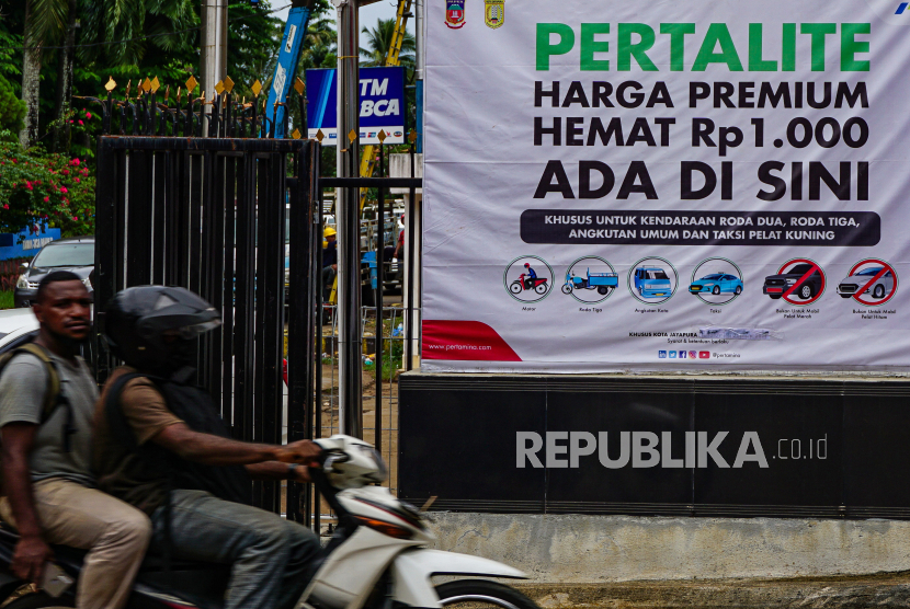 Pengendara melaju di samping spanduk harga promo BBM di SPBU A.P.O Kota Jayapura, Papua, Rabu (7/7). Pemerintah berencana menghapuskan premium dan pertalite dari pasaran dalam rangka transisi energi. 