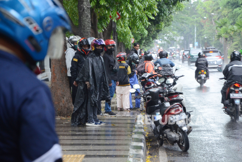 Pengendara motor memenuhi trotoar Jalan Diponegoro, untuk memakai jas hujan di bawah rindangnya pohon saat hujan deras mengguyur Kota Bandung. (ilustrasi)