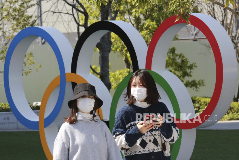  Orang-orang berjalan melewati ring Olimpiade di Tokyo, Rabu (17/3). Penyelenggara berencana untuk sangat berhati-hati saat estafet obor Olimpiade dimulai minggu depan. Mereka tahu setiap kesalahan bisa membahayakan pembukaan Olimpiade Tokyo hanya dalam empat bulan.