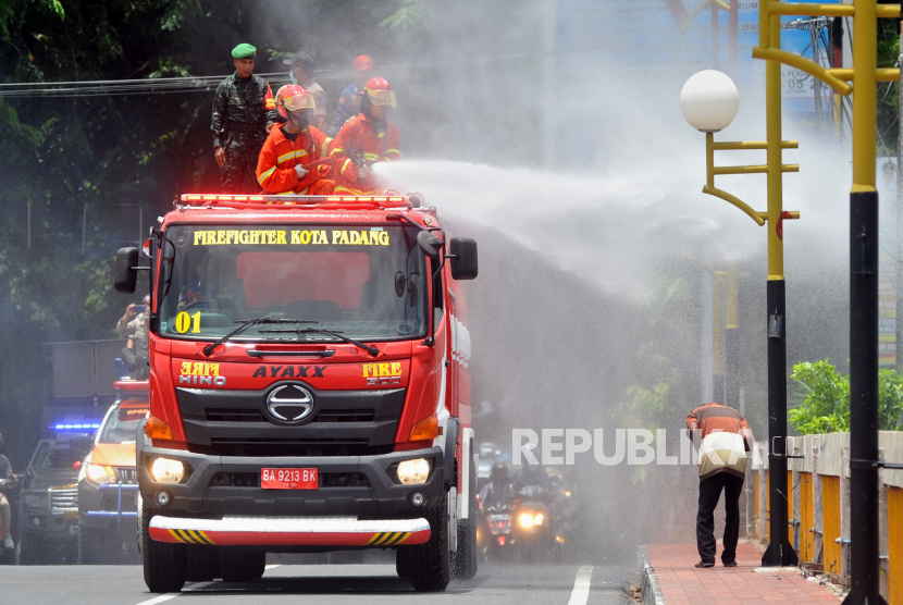 Petugas pemadam kebakaran menyemprotkan cairan disinfektan ke fasilitas umum di Padang, Sumatera Barat, Senin (23/3). Instruksi Wali Kota Padang menutup seluruh tempat hiburan malam sebagai bentuk pencegahan penyebaran Covid-19.