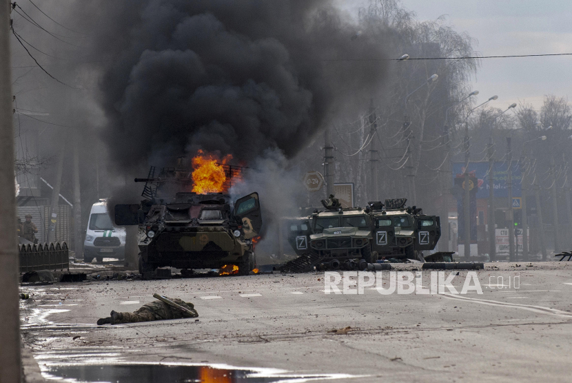 Sebuah pengangkut personel lapis baja Rusia terbakar di tengah kendaraan utilitas ringan yang rusak dan terbengkalai setelah pertempuran di Kharkiv, Ukraina, Ahad, 27 Februari 2022. 