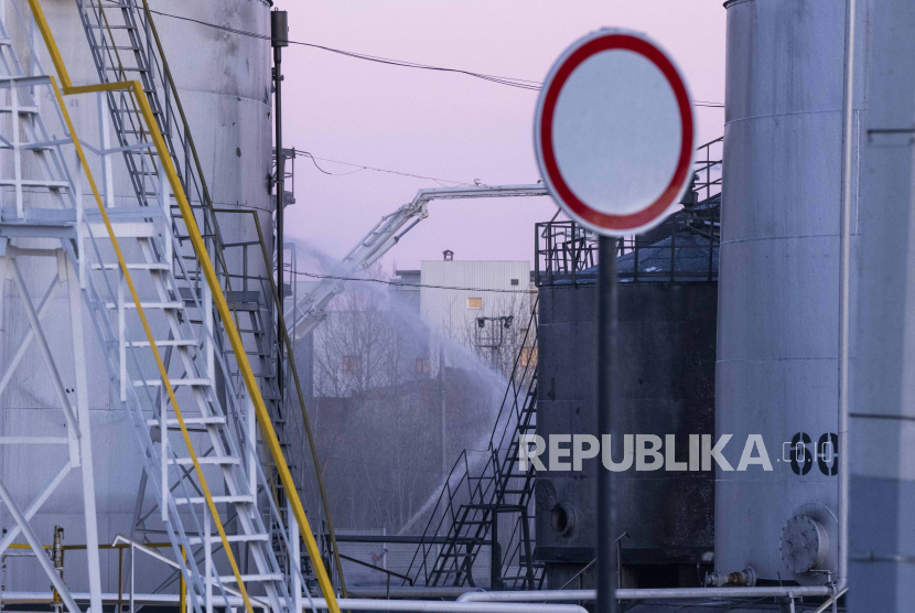 Petugas pemadam kebakaran menyemprot ke lokasi setelah serangan pertama yang melibatkan roket Rusia yang menghantam fasilitas minyak di kawasan industri di pinggiran timur laut Lviv, Ukraina, Ahad, 27 Maret 2022.