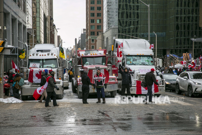 Pengemudi truk dan lainnya memprotes pembatasan pandemi COVID-19 di Ottawa, Ontario, pada Sabtu, 12 Februari 2022. Seorang hakim telah memerintahkan pengunjuk rasa di Jembatan Duta Besar di atas perbatasan AS-Kanada untuk mengakhiri blokade berusia 5 hari yang telah mengganggu arus barang antara kedua negara dan memaksa industri otomotif di kedua belah pihak untuk menghentikan produksi.
