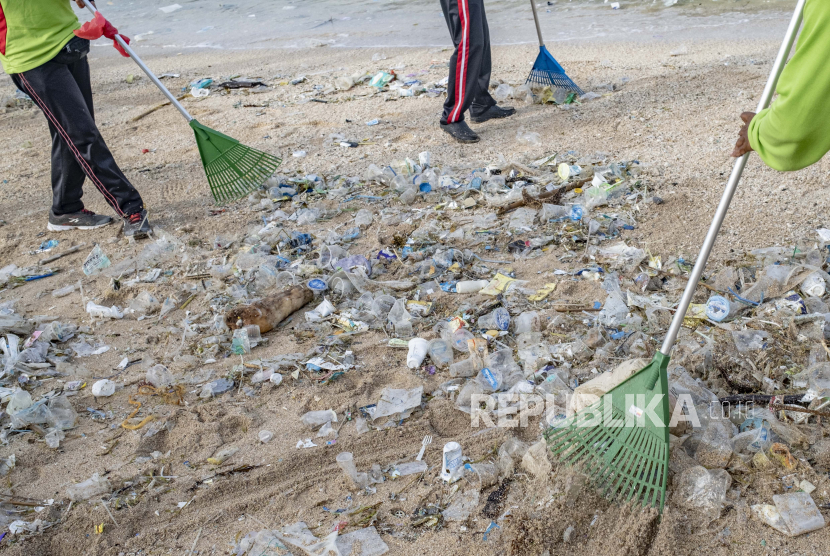  Pekerja membersihkan tumpukan puing dan sampah plastik yang dibawa oleh gelombang kuat di Pantai Kuta di Bali, Indonesia, 01 Januari 2021.