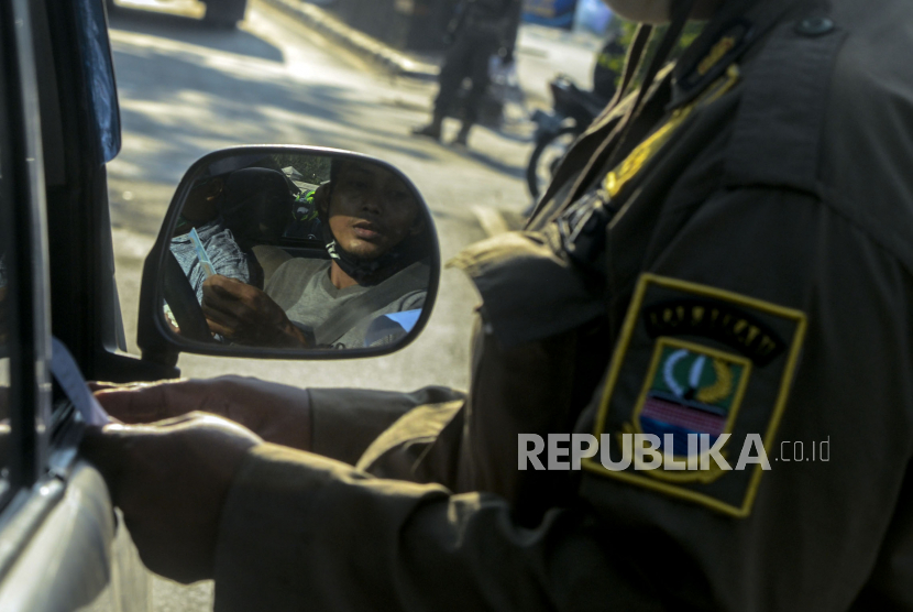 Petugas Satpol PP saat memeriksa dokumen pengendara yang akan memasuki wilayah DKI Jakarta di perbatasan Bekasi-Karawang, Jawa Barat, Jumat (29/5). Polda Metro Jaya mengingatkan bahwa pemudik yang kembali ke Jakarta wajib mengantongi surat bebas Covid-19. 