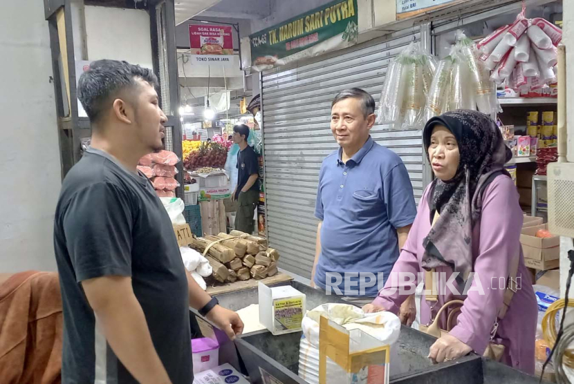 Salah seorang pedagang beras di Pasar Kosambi, Kota Bandung Andri tengah melayani pembeli, Senin (12/2/2024). 