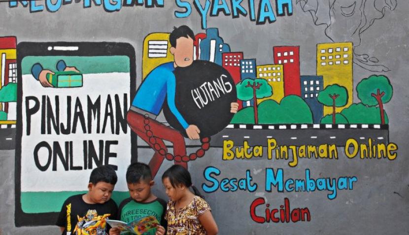 Sejumlah anak membaca bersama di dekat dinding bermural di kawasan Tempurejo, Surabaya, Jawa Timur, Selasa (7/9/2021). Mural tersebut sebagai sarana imbauan kepada masyarakat terhadap bahaya pinjaman daring atau 'online' (pinjol) ilegal yang sekarang lagi marak. (Antara/Didik Suhartono)