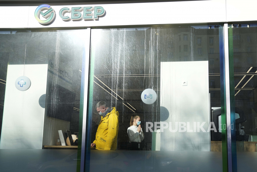 Seorang pelanggan, kiri, dan seorang karyawan di kantor Sberbank, di Moskow, Rusia, Rabu, 2 Maret 2022. Rusia akan memulai proyek percontohan menggunakan rubel 