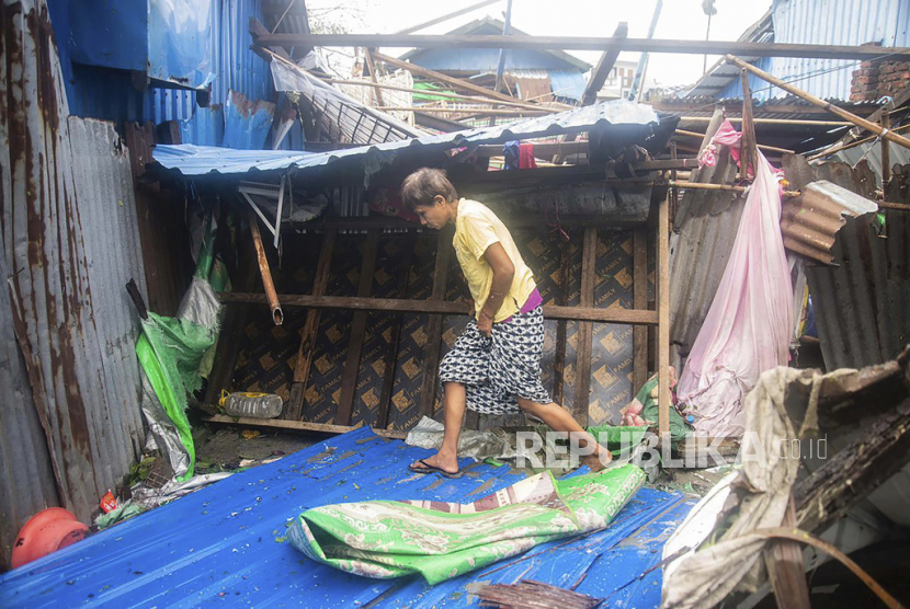 Seorang wanita berjalan melewati bangunan yang rusak setelah Topan Mocha di kotapraja Sittwe, Negara Bagian Rakhine, Myanmar, Senin, 15 Mei 2023. Tim penyelamat pada Senin mengevakuasi sekitar 1.000 orang yang terjebak oleh air laut sedalam 3,6 meter (12 kaki) di sepanjang barat Myanmar