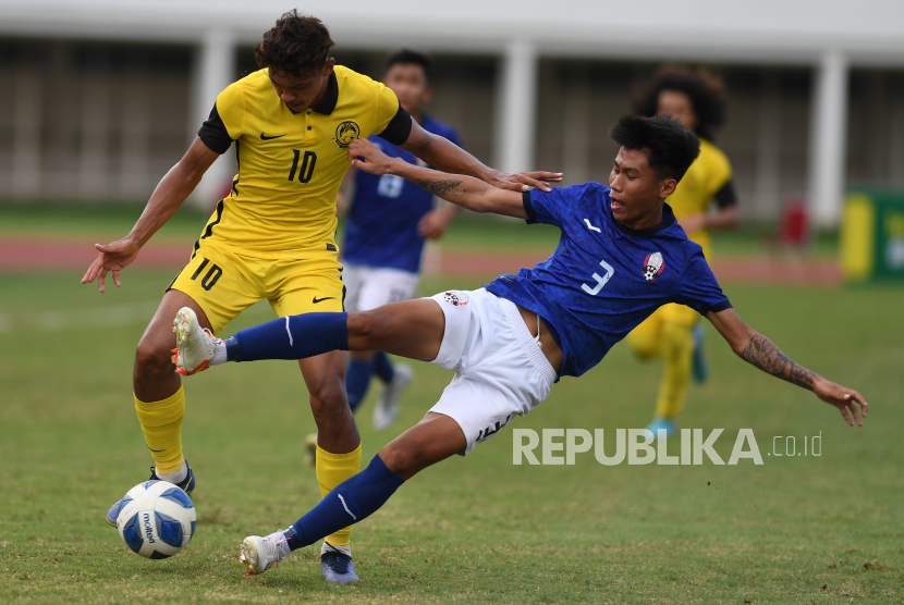 Pesepak bola Malaysia U19 Muhammad Haqimi Azim Rosli (kiri) berebut bola dengan pesepak bola Kamboja U19 Chhan Bun My (kanan) dalam laga penyisihan grup Piala AFF U19 di Stadion Madya Senayan, Jakarta, Selasa (5/7/2022). Malaysia U19 menang dengan skor 2-1. 