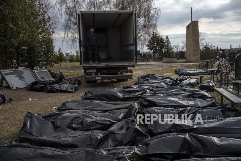 Seorang pekerja pemakaman menunggu di sebuah truk sebelum rekannya mulai memuat mayat warga sipil yang tewas di Bucha, sebelum mengangkut mereka ke kamar mayat, di pinggiran Kyiv, Ukraina, Rabu, 6 April 2022.