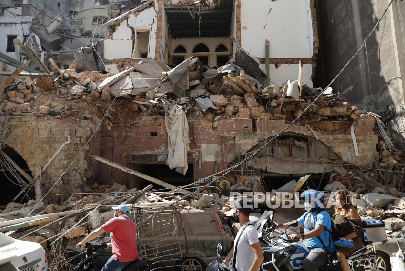 Warga mengendarai skuter dan sepeda motor di depan sebuah rumah yang hancur akibat ledakan dahsyat Selasa di pelabuhan Beirut, Lebanon, Rabu, 5 Agustus 2020.
