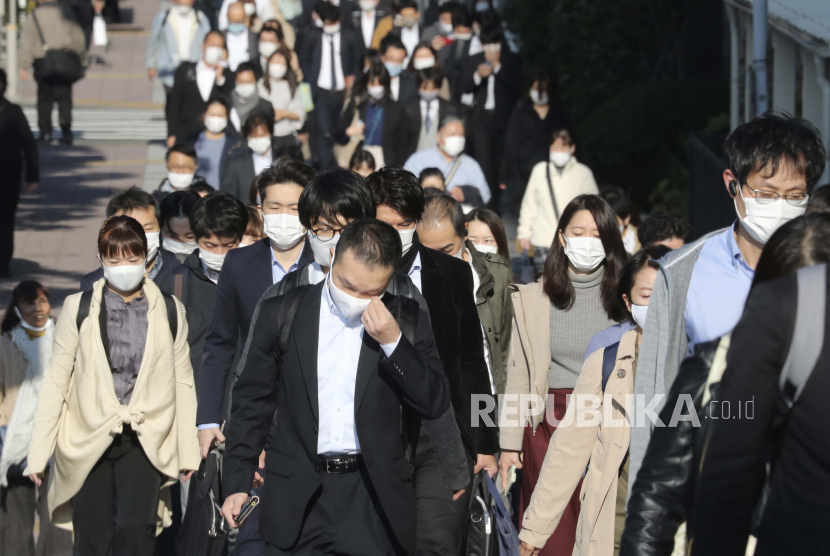  Para penumpang yang memakai masker wajah untuk melindungi dari penyebaran virus corona berjalan di sebuah jalan di Tokyo, Selasa, 17 November 2020.