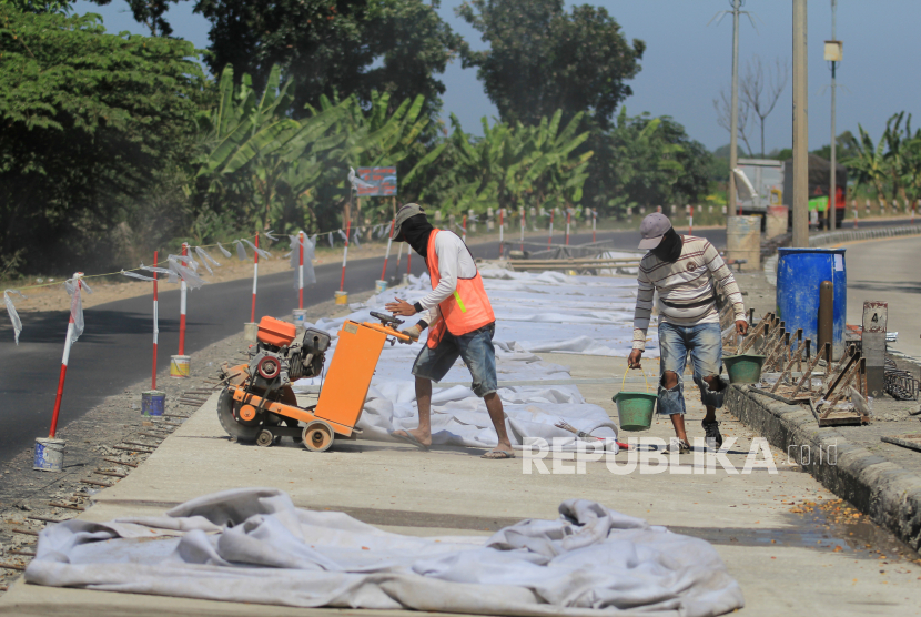 Pekerja menyelesaikan pekerjaan pembetonan jalan di jalur Pantura Lohbener, Indramayu, Jawa Barat, Senin (27/7). PUPR mencatat realisasi belanja infrastruktur tahun 2020 telah mencapai 44 persen dalam rangka mendorong pemulihan ekonomi nasional.