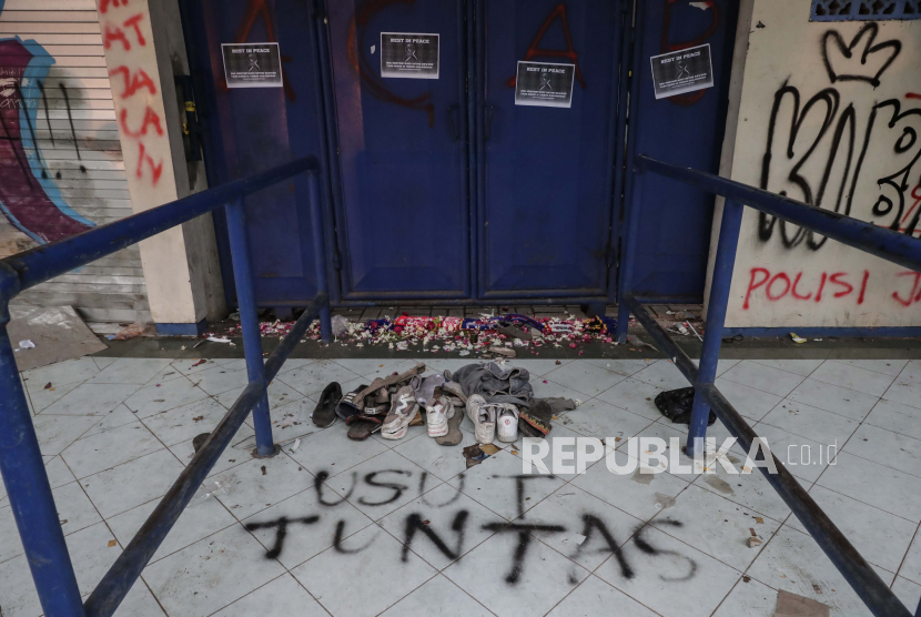 Tumpukan sepatu milik korban kerusuhan dan penyerbuan pertandingan sepak bola terlihat dengan tulisan ?Selidiki tuntas? di Stadion Kanjuruhan Malang, Jawa Timur