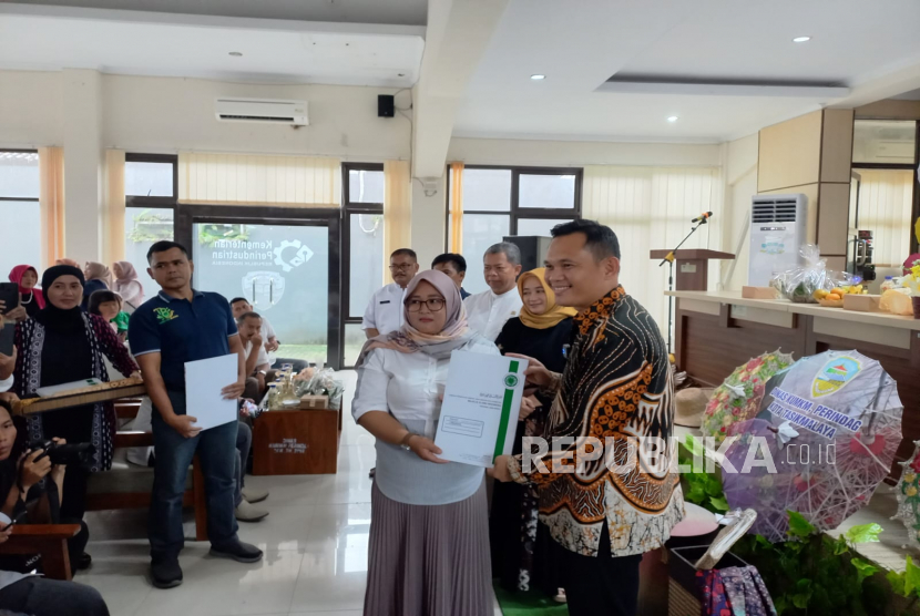 Penjabat (Pj) Wali Kota Tasikmalaya Cheka Virgowansyah (kanan) menyerahkan sertifikat halal kepada pelaku IKM olahan makanan di PPIK Kota Tasikmalaya, Jawa Barat, Jumat (20/1/2023). 