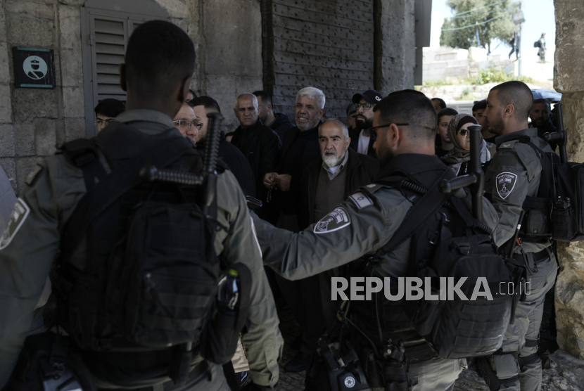 Polisi Perbatasan Israel menyaksikan jamaah Muslim berjalan ke kompleks Masjid Al-Aqsa untuk salat Jumat kedua di bulan suci Ramadhan di Kota Tua Yerusalem, Jumat, (22/3/2024).