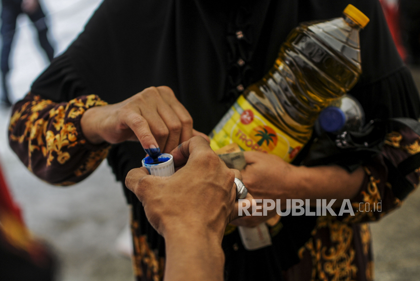 Warga yang telah membeli minyak goreng mencelupkan jarinya ke tinta saat operasi pasar di Polsek Tebet, Jakarta Selatan, Jumat (4/3/2022). 