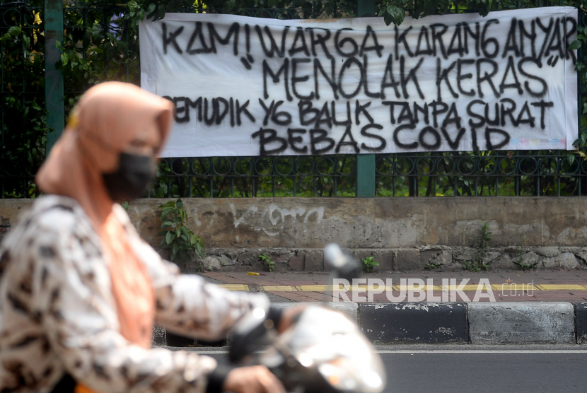 Pengendara melintas di dekat spanduk peringatan untuk pemudik di kawasan Karang Anyar, Jakarta, Ahad (23/5). Tren jumlah kasus Covid-19 yang meningkat pascalebaran diantisipasi oleh Menteri Keuangan Sri Mulyani dengan melakukan penghematan anggaran.