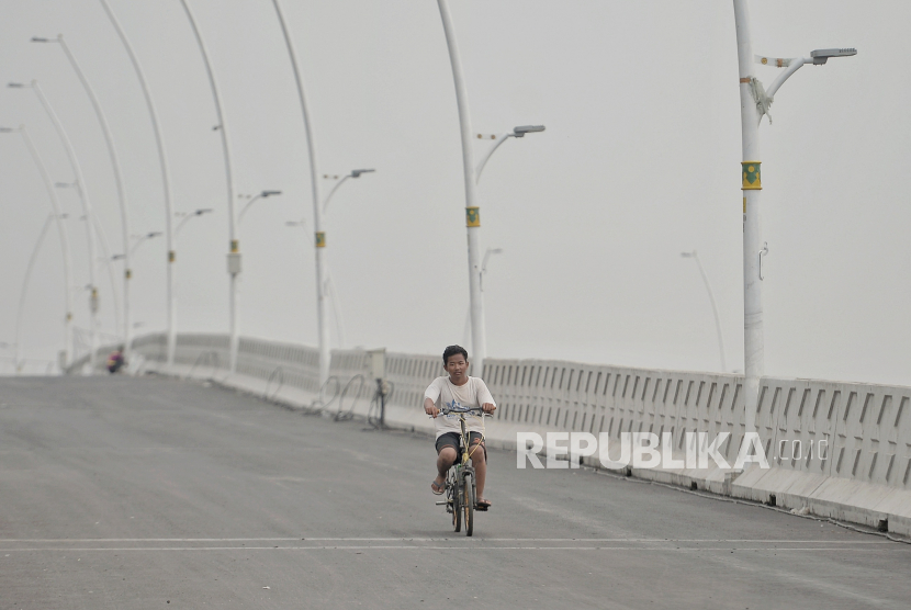 Warga menaiki sepeda melintas di area pembangunanan lintas atas Cakung di Jakarta Timur, Selasa (16/3). 