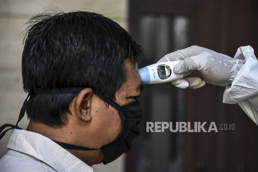 Petugas medis memeriksa suhu tubuh orang dengan status risiko corona, ilustrasi