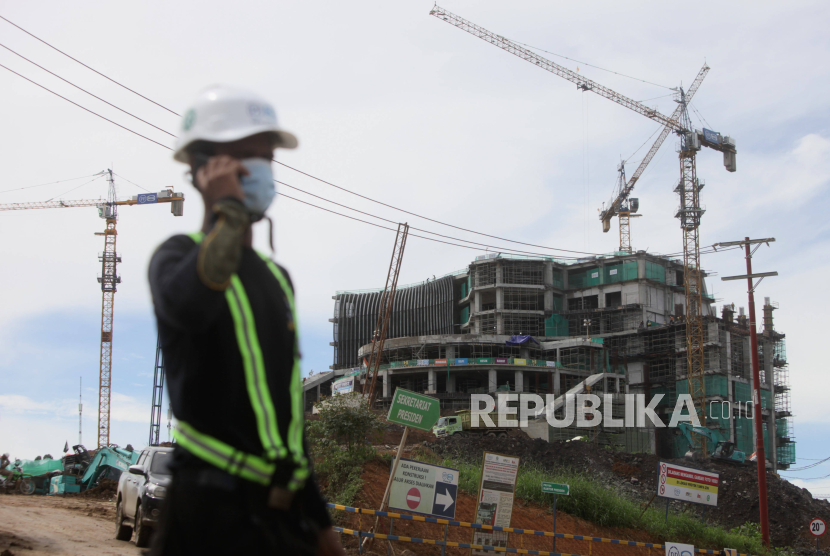 Pekerja berjalan dengan latar belakang pembangunan Istana Negara di Kawasan Inti Pusat Pemerintahan (KIPP) Ibu Kota Negara (IKN) Nusantara, Penajam Paser Utara, Kalimantan Timur, Kamis (7/12/2023).