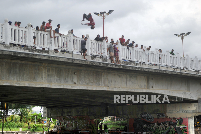 Sejumlah remaja berkerumun menyaksikan teman mereka melompat ke sungai di Jembatan Purus, Padang.