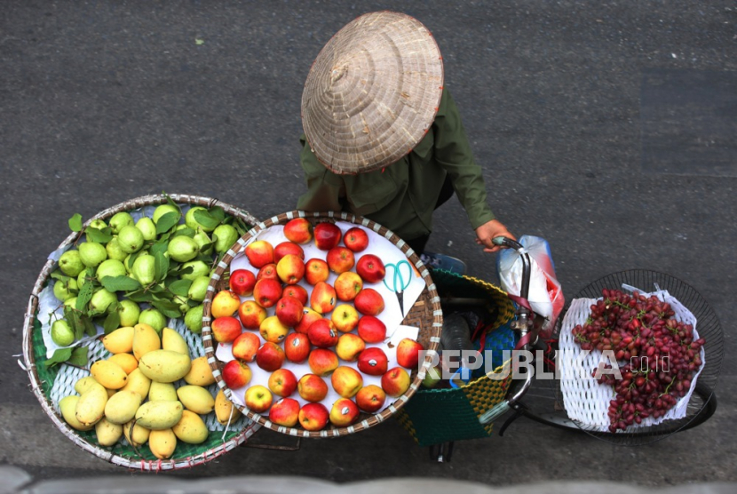 Seorang pedagang kaki lima yang menjual buah-buahan berjalan di sepanjang jalan di Hanoi, Vietnam, Kamis (12/10/2023).