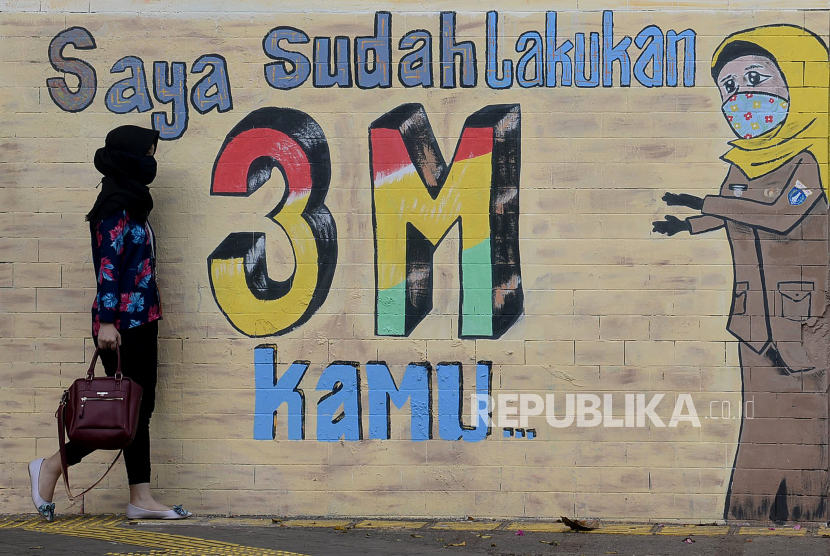 Pejalan kaki melintasi mural bertemakan kampanye protokol kesehatan Covid-19 di sekitar Terowongan Stasiun Cawang, Jakarta. Jumat (9/10) ini, kasus positif dilaporkan bertambah 4.094 orang dalam 24 jam terakhir. 