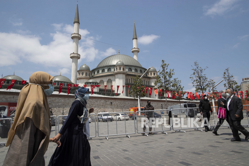Orang-orang berjalan di depan Masjid Taksim yang baru dibangun di Alun-alun Taksim saat upacara pembukaan masjid dengan dihadiri oleh Presiden Turki Recep Tayyip Erdogan (tidak dalam foto) di Istanbul, Turki, 28 Mei 2021. 