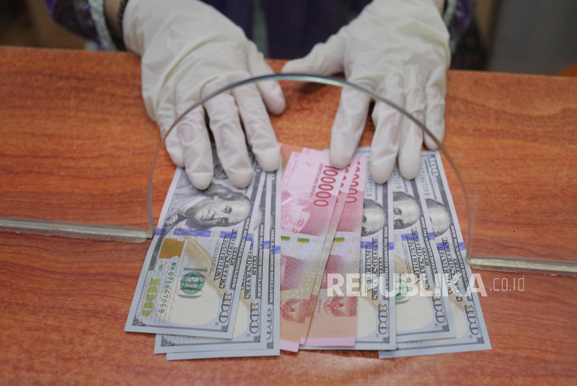 Petugas menunjukkan uang rupiah dan dolar AS di salah satu gerai penukaran mata uang asing di Jakarta. ilustrasi
