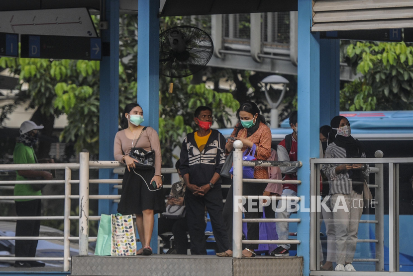 Sejumlah warga menggunakan masker saat menunggu bus Transjakarta di kawasan Sudirman, Jakarta, Rabu (14/10). PT Transportasi Jakarta (Transjakarta) kembali melakukan modifikasi rute layanan sebagai antisipasi dari aksi buruh dan mahasiswa, Selasa (20/10).