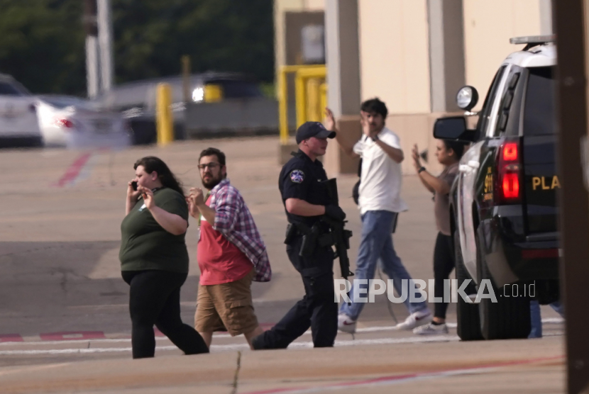 Orang-orang mengangkat tangan saat meninggalkan pusat perbelanjaan menyusul laporan penembakan, Sabtu (6/5/2023), di Allen, Texas. 