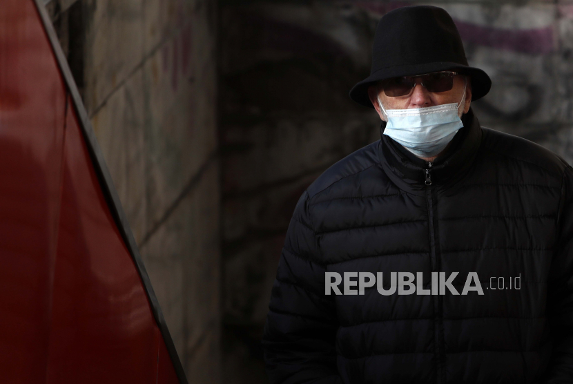  Seorang pria yang memakai masker wajah untuk melindungi dari virus corona berjalan di Beograd, Serbia, Selasa, 22 Desember 2020. Serbia pada Selasa menerima 4.800 dosis vaksin virus korona Pfizer-BioNTech.