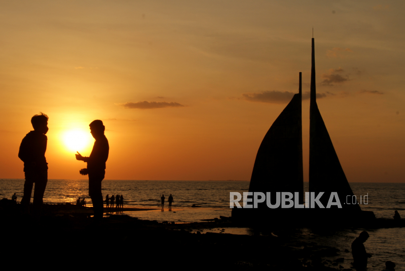 Pengunjung menikmati suasana matahari tenggelam di Pantai Tanjung Layar Putih, Makassar, Sulawesi Selatan