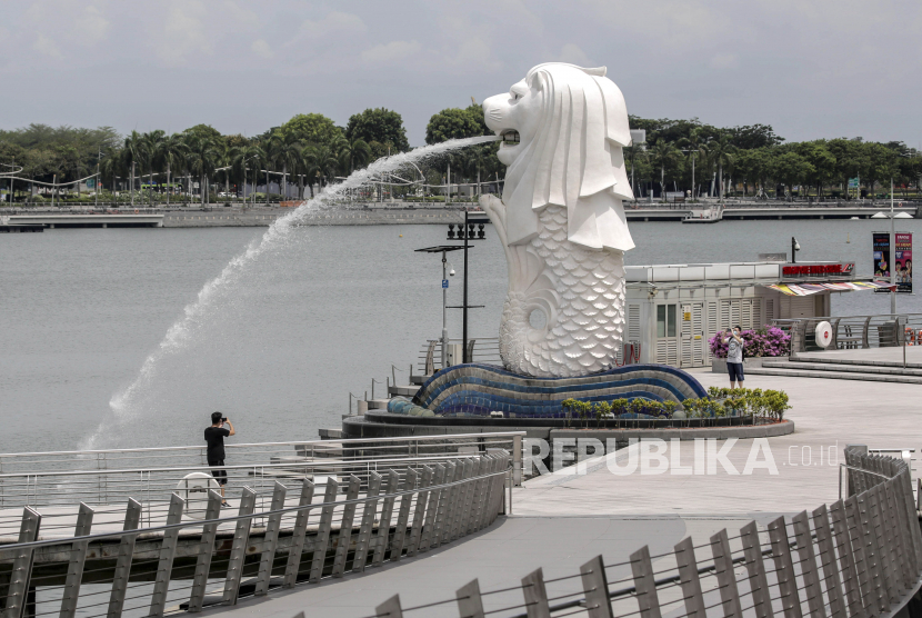 Dua pria mengambil foto patung Merlion di Singapura (ilustrasi). Kepolisian Singapura berhasil mengungkap kasus pencucian uang terbesar di negara tersebut.